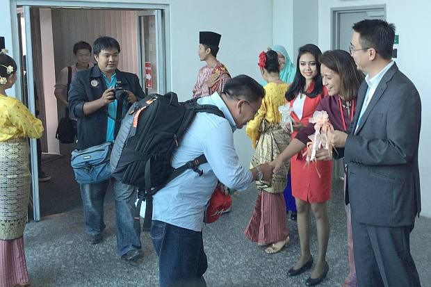 Aireen (second from right) and Md Derick (right) greeting passengers from the Hat Yai flight at Senai International Airport in Johor Baru on Friday.
